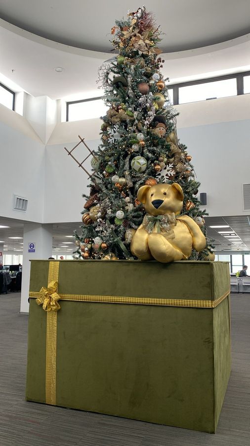 Árbol de navidad dorado con oso gigante en lobby corporativo